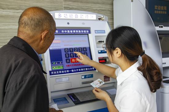 服務(wù)人員通過掛號自助機為老人預(yù)約專家。潘迎霞 攝